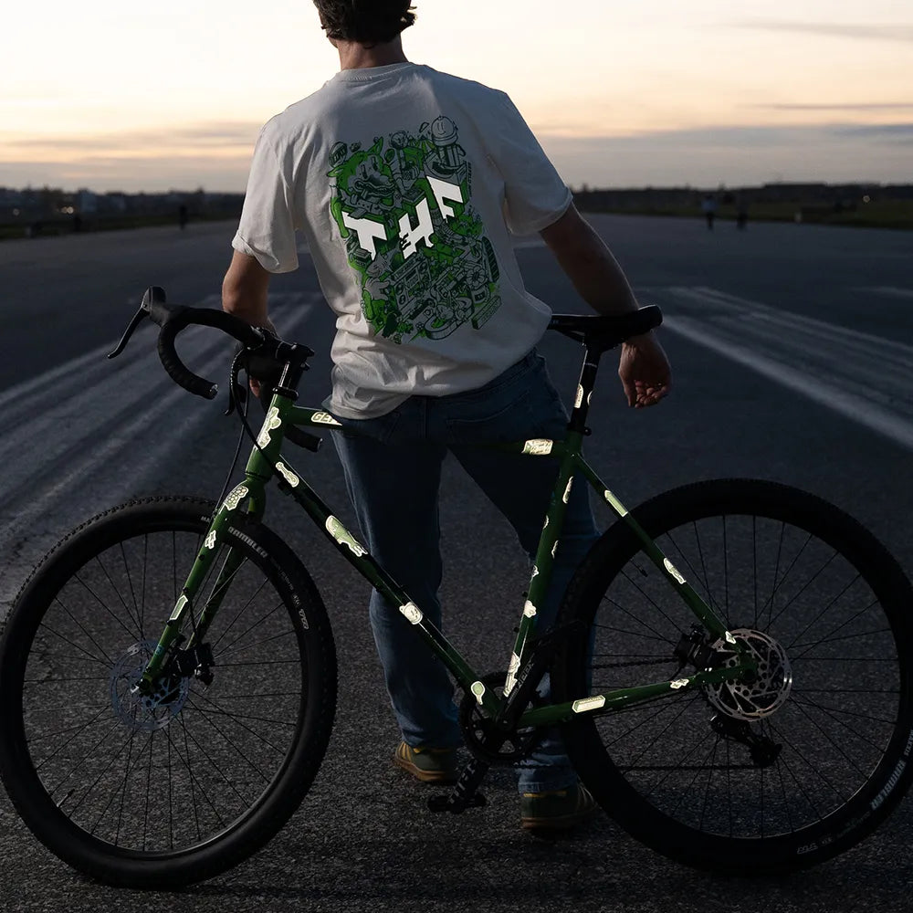 Reflektierende Aufkleber Tempelhofer Feld Themenwelt von REFLECTIVE Berlin auf einem grünen Gravelbike in der Gesamtansicht mit sichtbarer Reflexion und passendem T-Shirt aus der Kollektion auf dem Tempelhofer Feld.