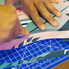 Reflektierende Aufkleber Folie XXL „Flamingo Funk“ wird von einer Hand mit Cuttermesser auf einem Schneidebrett zugeschnitten. Arrangement von REFLECTIVE Berlin.