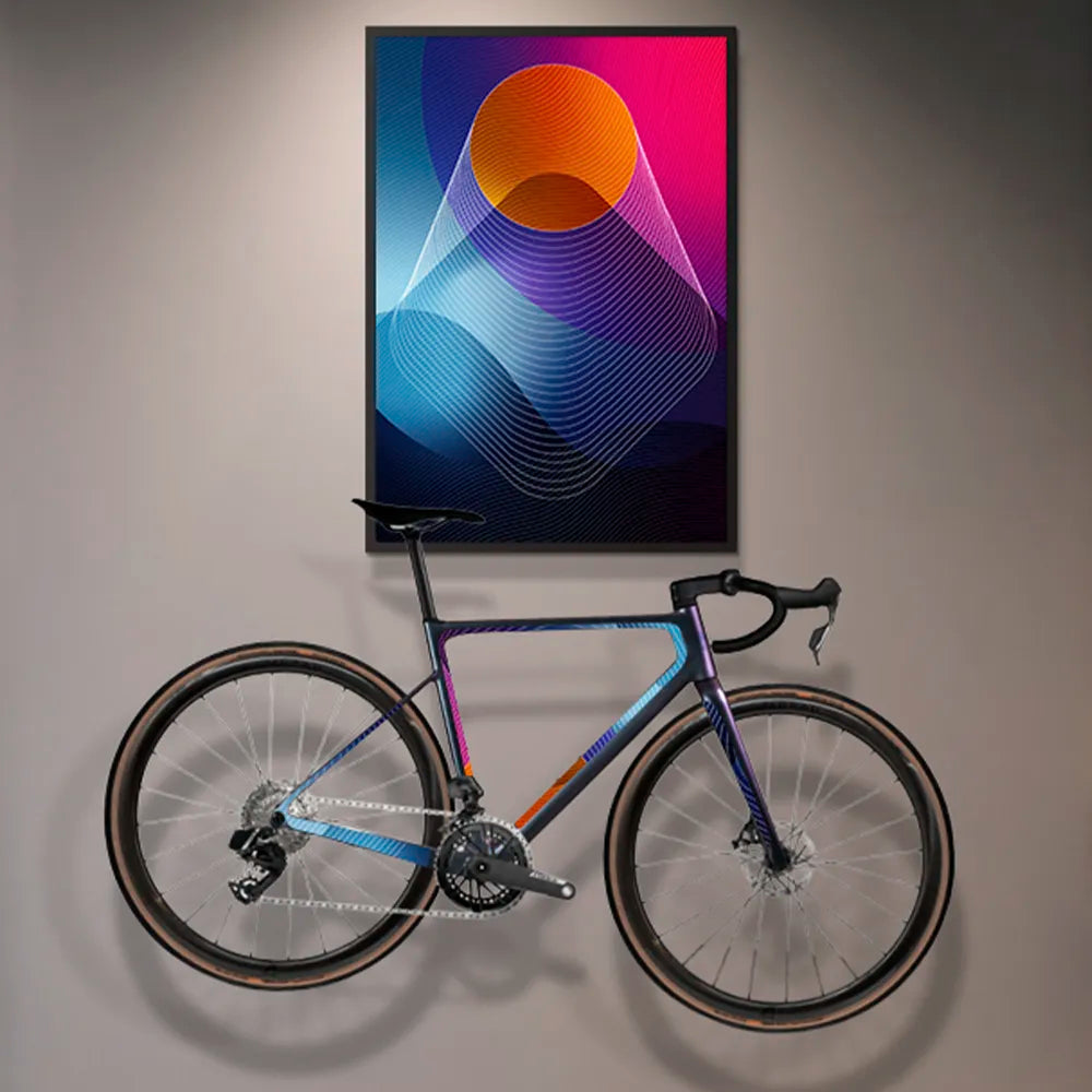Reflektierende Aufkleber Folie XXL „Venus“ mit abstrakten Formen in Blauen, orangen und pinken Farbtönen, in Bilderrahmen, der über einem Rennrad an der Wand hängt. Das Rennrad ist mit zugeschnittenen Sticker Elementen aus der Aufkleber Folie beklebt. Arrangement von REFLECTIVE Berlin.