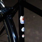 Reflektierende Aufkleber Künstleredition „Kurihara“ auf schwarzem Fahrrad Rahmen vor unscharfem Hintergrund. von REFLECTIVE Berlin