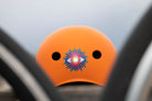 Reflektierender Aufkleber „Auge“ in Farbvariante „Regenbogen“ auf orangem Fahrradhelm Rückansicht. Von REFLECTIVE Berlin.