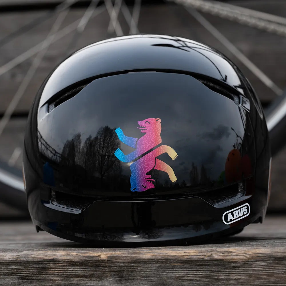 Zwei Reflektierendee Aufkleber „Berliner Bär“ in Farbvariante „Regenbogen“ zugeschnitten auf schwarzem Fahrradhelm Rückansicht. Von REFLECTIVE Berlin.