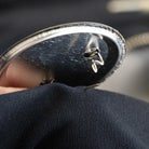 Reflektierender Button Anstecker “Berge“ in Detail Rückansicht mit sichtbarer Sicherheitsnadel. Arrangement von REFLECTIVE Berlin.