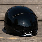 Reflektierender Aufkleber „Cargo“ in Farbvariante „weiß“ auf schwarzem Fahrradhelm Frontansicht vor unscharfem Hintergrund von REFLECTIVE Berlin.