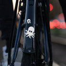 Reflektierender Aufkleber „Oktopus“ in Farbvariante „weiß“ auf schwarzem Fahrrad Schutzblech vor unscharfem Hintergrund. Von REFLECTIVE Berlin.
