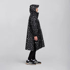 reflektierender Fahrrad Regenponcho in Farbvariante „Doodle“ getragen von einer Person, die im Profil steht und nach rechts schaut vor weißem Hintergrund. Kollaboration von Bomance und REFLECTIVE Berlin.