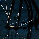 Reflektierender Speichen Aufkleber „Spokes“ in Farbvariante „weiß“ auf den Speichen von einem Vorderrad eines Fahrrads. Blitzlicht hebt die Reflexion hervor. Von REFLECTIVE Berlin.