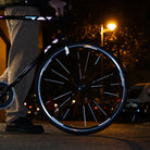 Reflektierender Speichen Aufkleber „Spokes“ in Farbvariante „weiß“ auf den Speichen von einem Vorderrad eines Fahrrads. Blitzlicht hebt die Reflexion hervor. Auf dem Fahrradrahmen und Gabel kleben reflektierende Aufkleber „Delta“, Farbvariante „Spacebaby“ von REFLECTIVE Berlin.
