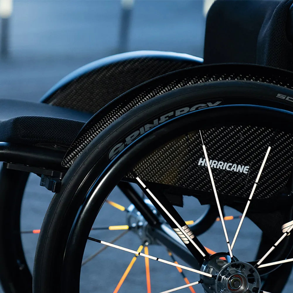 Reflektierender Speichen Aufkleber „Spokes“ in Farbvariante „weiß“ und „Feuer" auf den Speichen von einem Rollstuhl. Blitzlicht hebt die Reflexion hervor. Von REFLECTIVE Berlin.