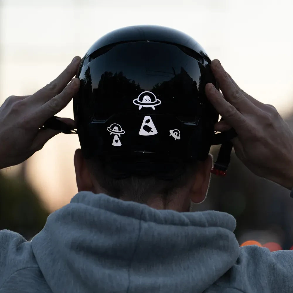 Reflektierender Aufkleber „UFO“ in Farbvariante „weiß“ auf Rückseite von einem schwarzem Helm von REFLECTIVE Berlin.