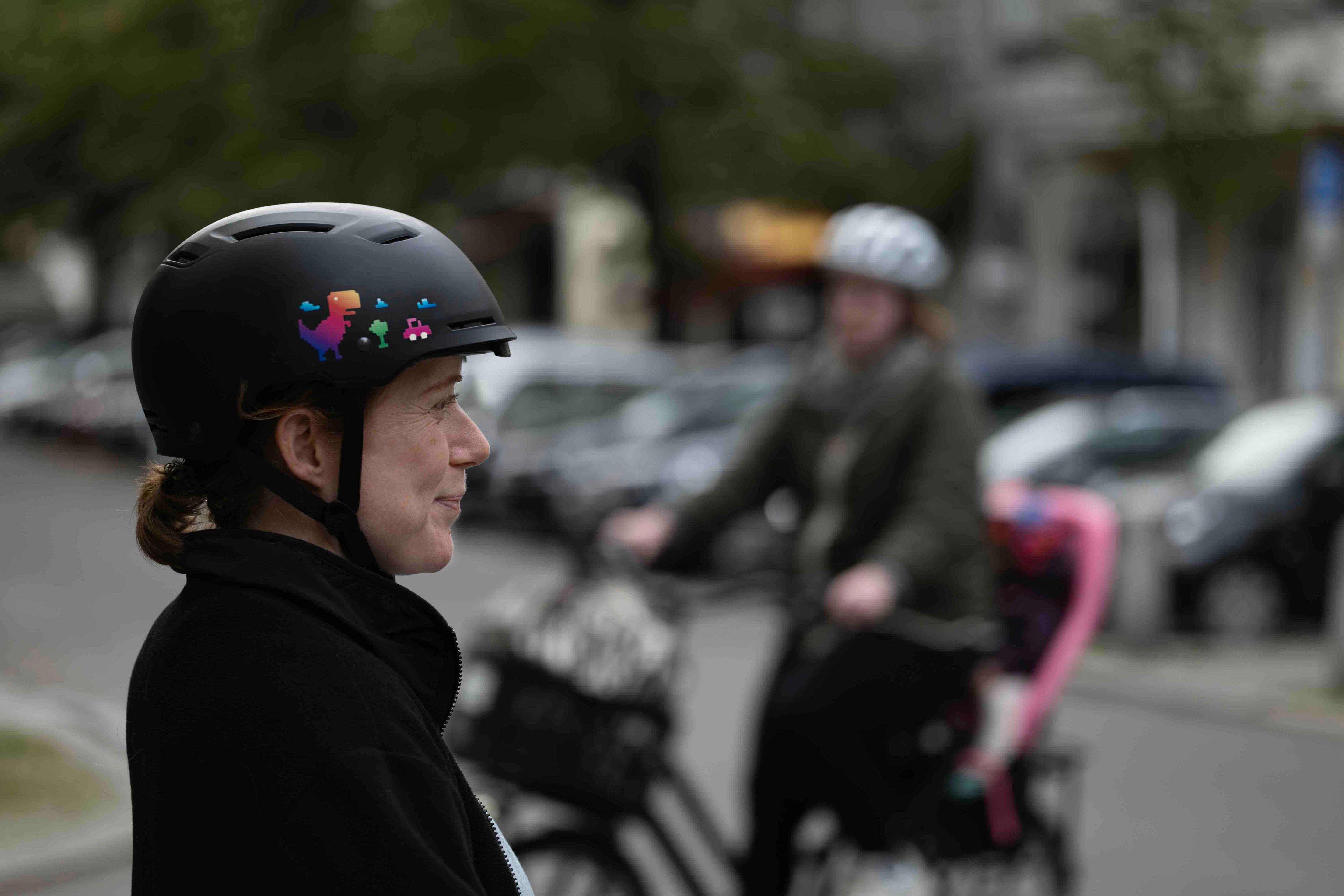 T-Rex Rainbow von REFLECTIVE Berlin auf schwarzem Fahrradhelm mit stark reflektierendem mehrfarbigem Dinosauriermotiv für mehr Sichtbarkeit im urbanen Stil.