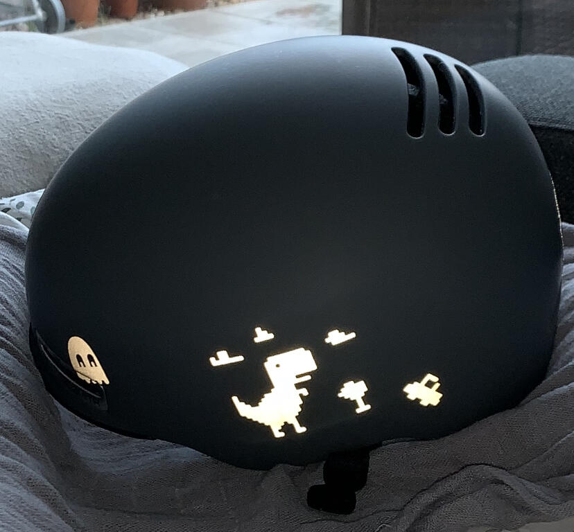 Weißer T-Rex Sticker von REFLECTIVE Berlin auf Fahrradhelm mit stark reflektierendem Dinosauriermotiv für mehr Sichtbarkeit im urbanen Stil.