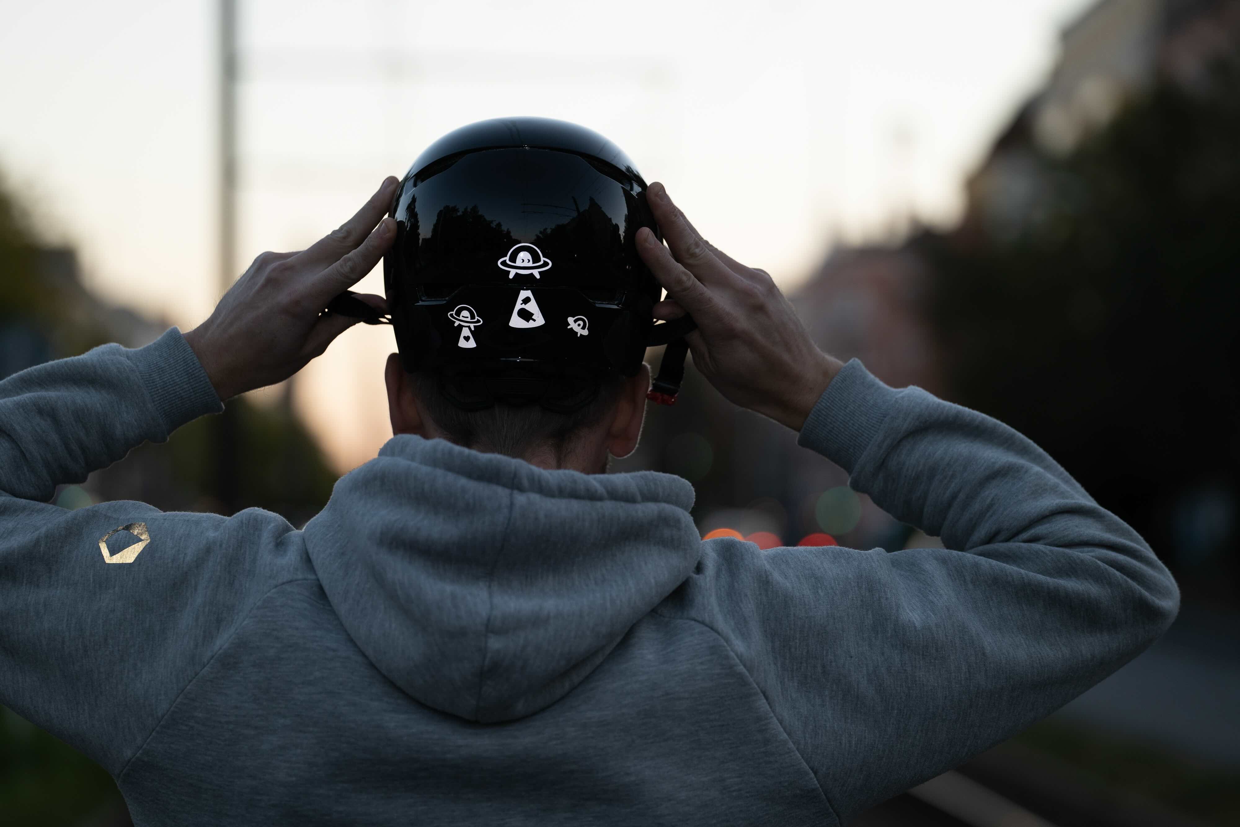 Ufo Weiß von REFLECTIVE Berlin auf schwarzem Fahrradhelm mit stark reflektierendem Ufo-Motiv für mehr Sichtbarkeit im urbanen Stil.