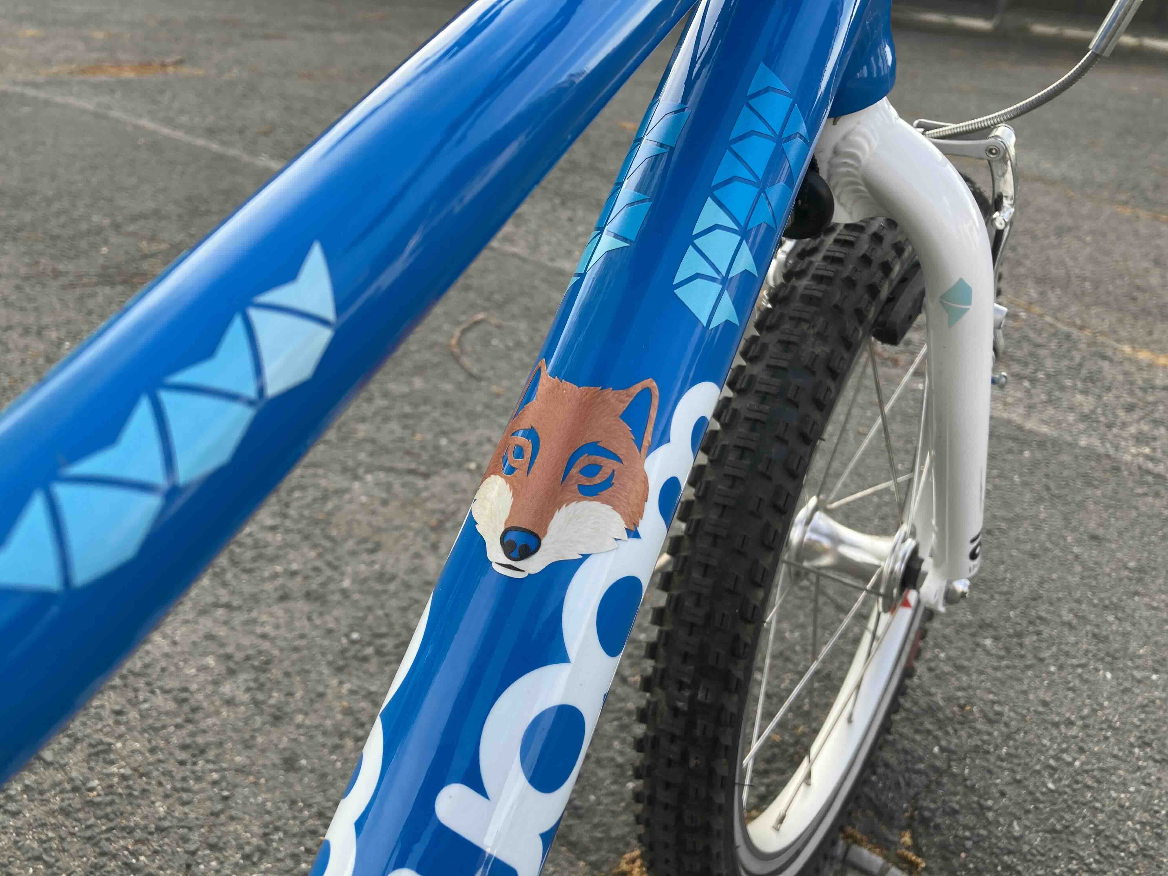Wolf Gold und Kites & Darts Blau von REFLECTIVE Berlin auf blauem Kinderfahrrad mit stark reflektierenden Tier- und Pfeilformen für mehr Sichtbarkeit im urbanen Stil.