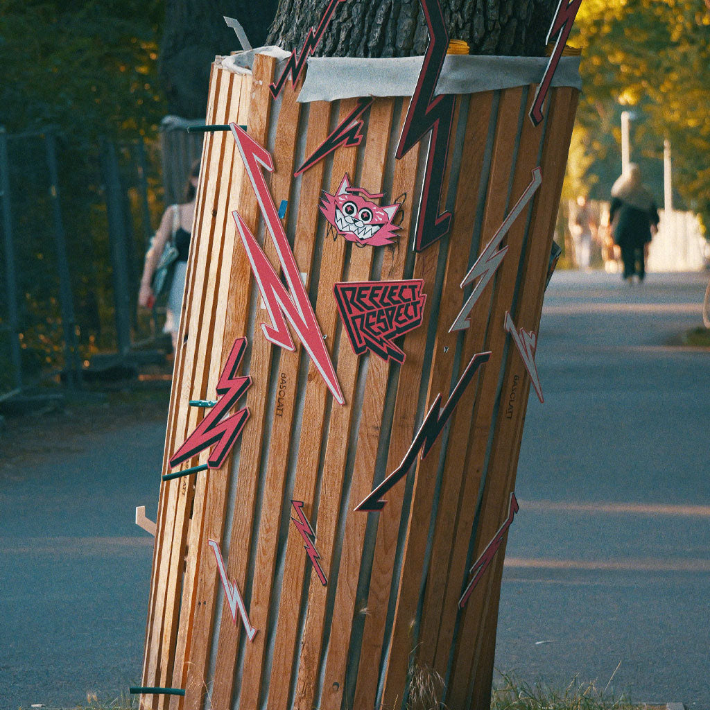 Baumstamm mit Holzgerüst das mit Formen aus Blitzen und einem Katzengesicht beklebt ist.