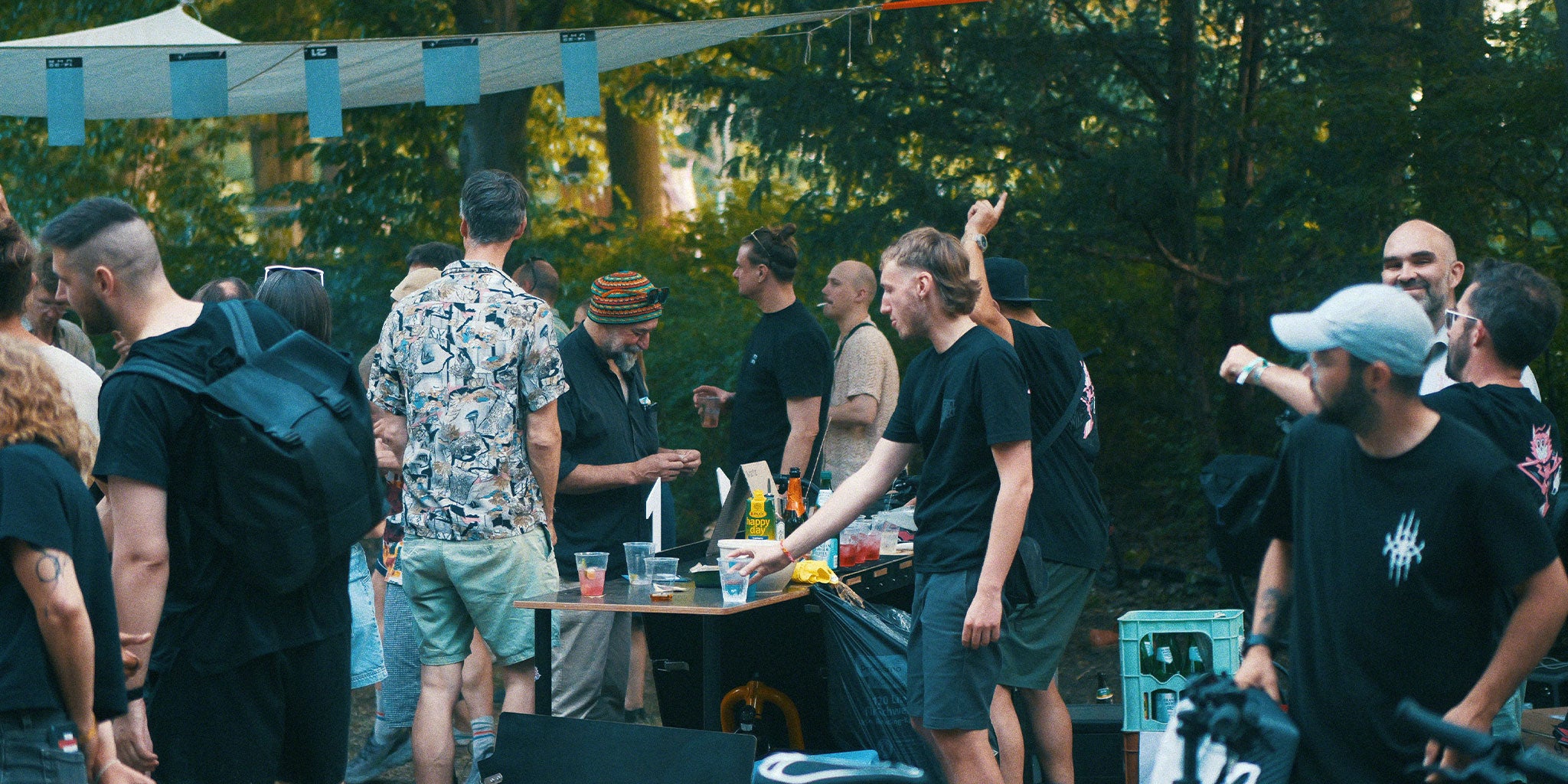 Menschen im Park stehen um eine mobile Bar und unterhalten sich oder tanzen