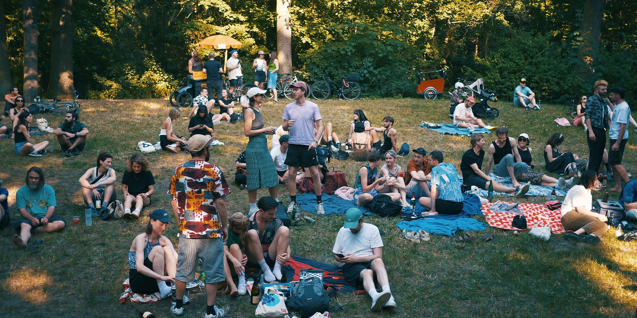 Viele Leute im Park sitzen auf Decken, chillen, trinken und unterhalten sich