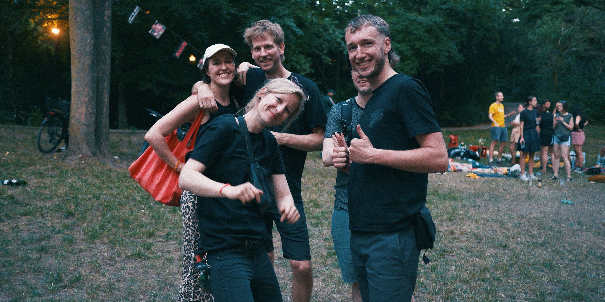 Gruppe an jungen Erwachsenen, die freundlich in die Kamera schauen und im Park stehen
