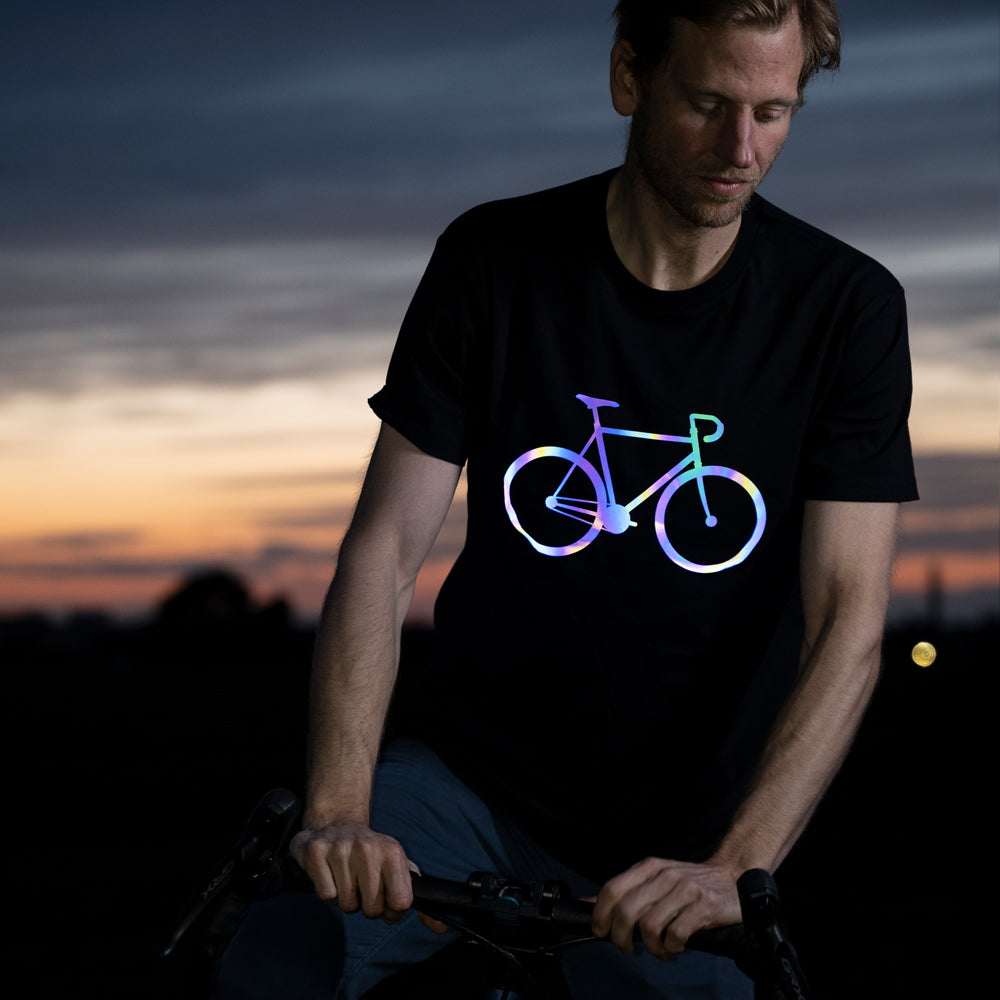 Guy grabbing dropbar of gravelbike, wearing reflective shirt with bicycle print