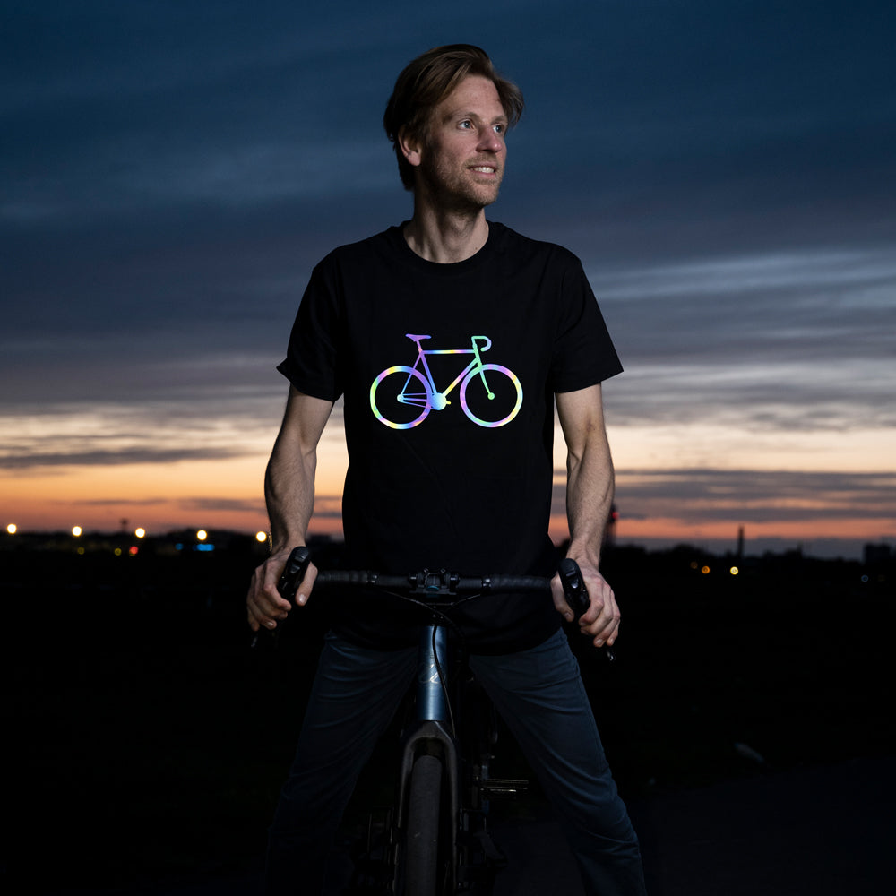 Fahrradfahrer auf Gravelbike vor Sonnenuntergang trägt ein schwarzes T-Shirt mit reflektierendem Fahrrad Aufdruck