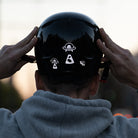 Man puting on his helmet, with reflective UFO stickers 