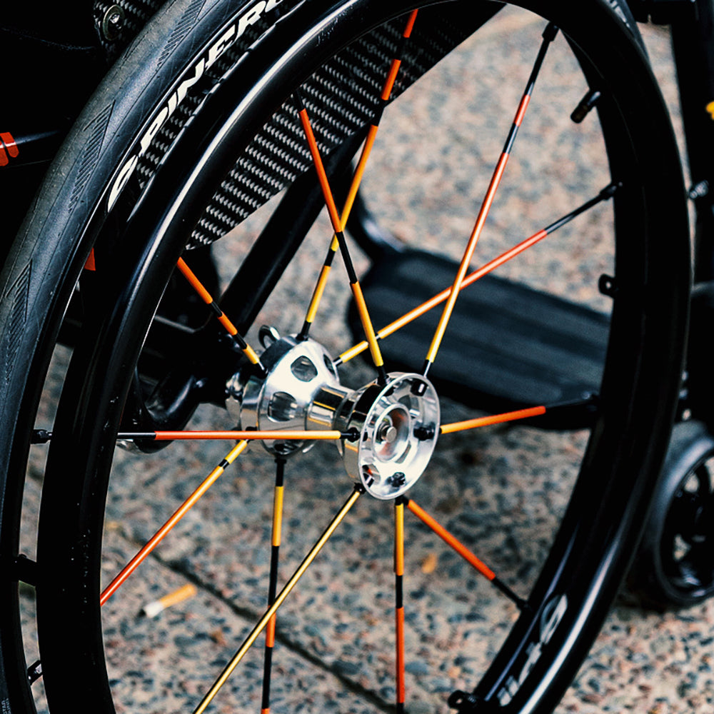 rechtes Laufrad am Rollstuhl, beklebt mit reflektierenden Stickern an den Speichen
