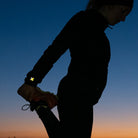 Joggerin strecht bei Sonnenuntergang nach dem Laufen, Reflektierender Aufkleber an Laufbekleidung