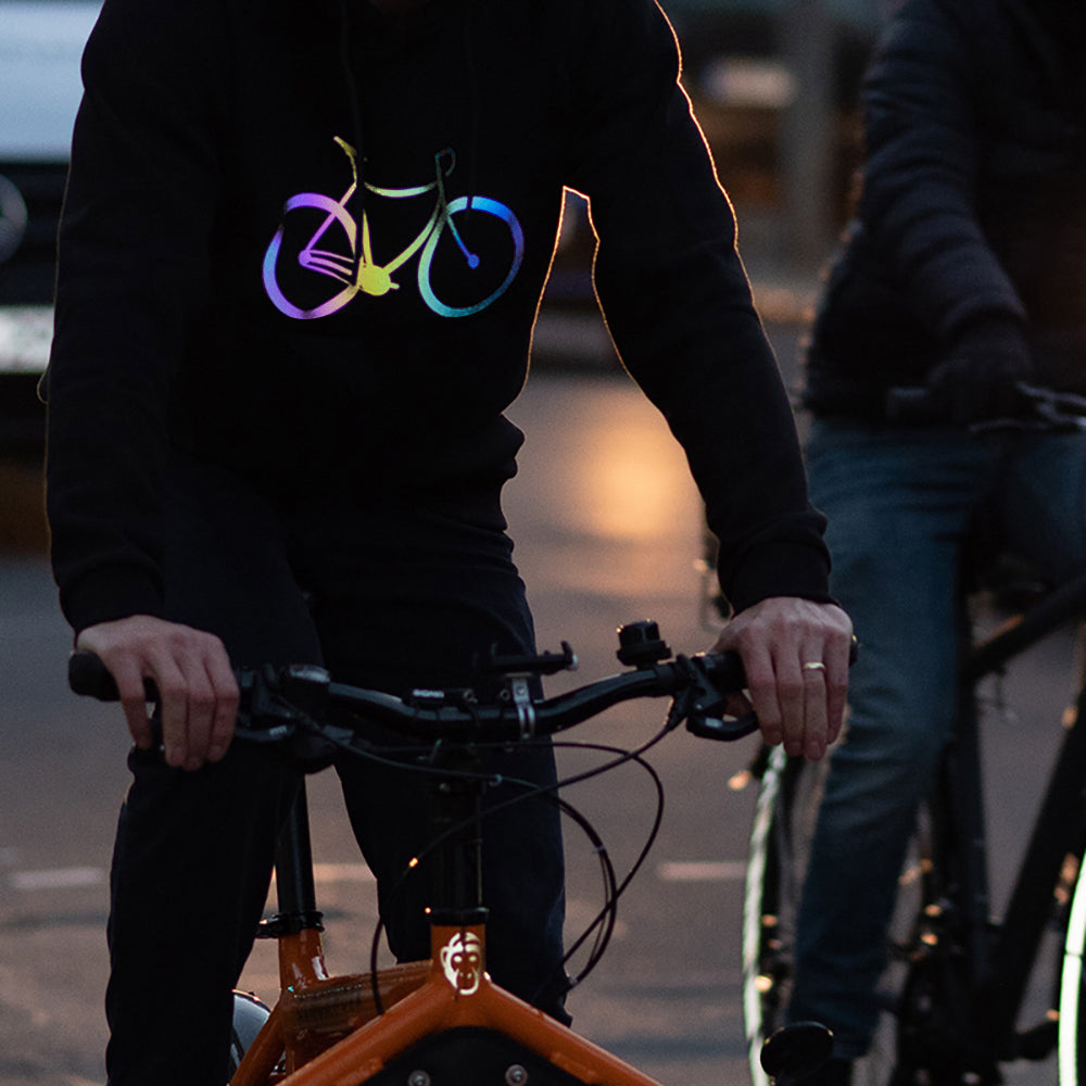 Fahrradfahrer eines orangenen Bullitts, im Verkehr abends, mit leuchtendem Fahrrad auf der Brust eines Kapuzenpullovers