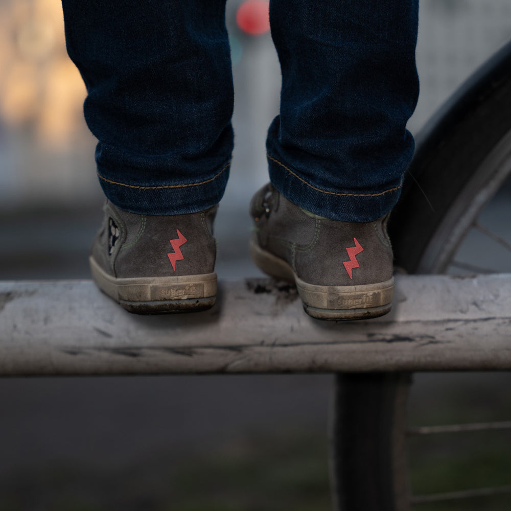 Rote Blitze Sticker, reflektierend, auf Kinderschuhen die auf einem Geländer stehen