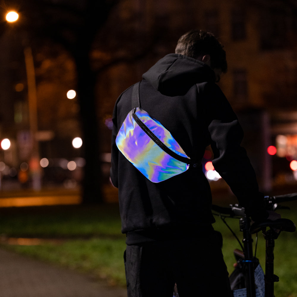 Man wearing the XL rainbow reflective pouch, and bicycle in dark street.