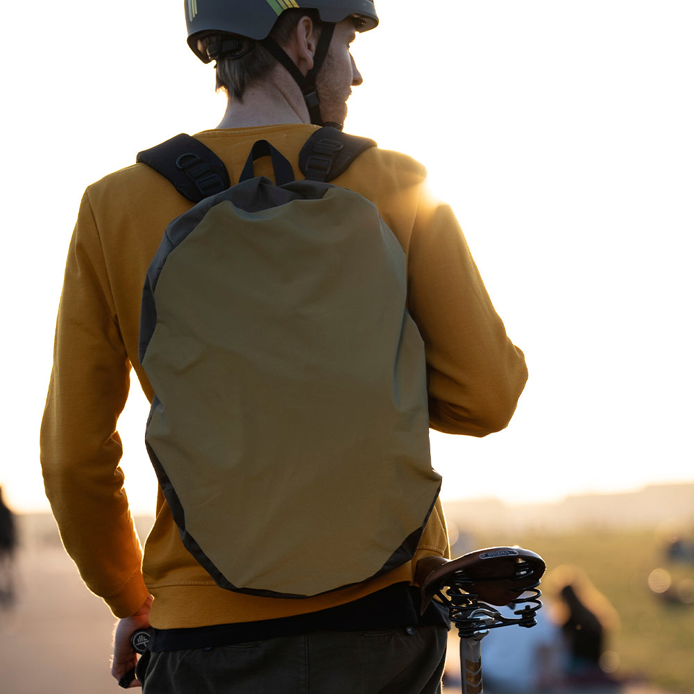 Radfahrer mit Helm und gelbem Pullover und oliv-grünen Rucksack auf dem Tempelhofer Feld
