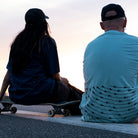 woman left and man right sitting, watching sunset, both wearing t-shirt with line print