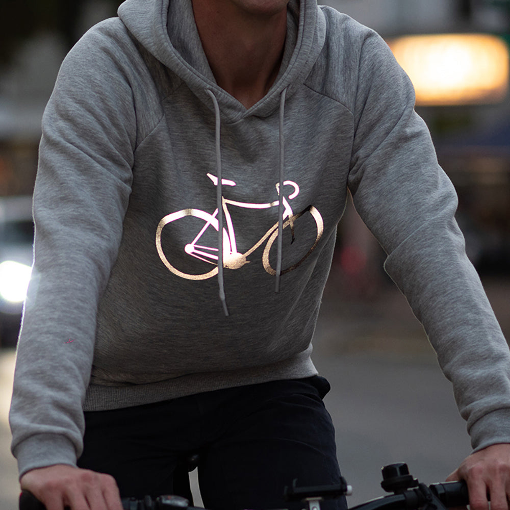 Radfahrender trägt grauen Kapuzenpullover mit hell leuchtendem Fahrrad Aufdruck vorne auf der Brust