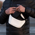 White arctic pouch in the day time with the use of a hand reaching for a smart phone