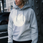 Frau trägt grauen Hoodie mit hell reflektierendem runden Aufdruck vorne