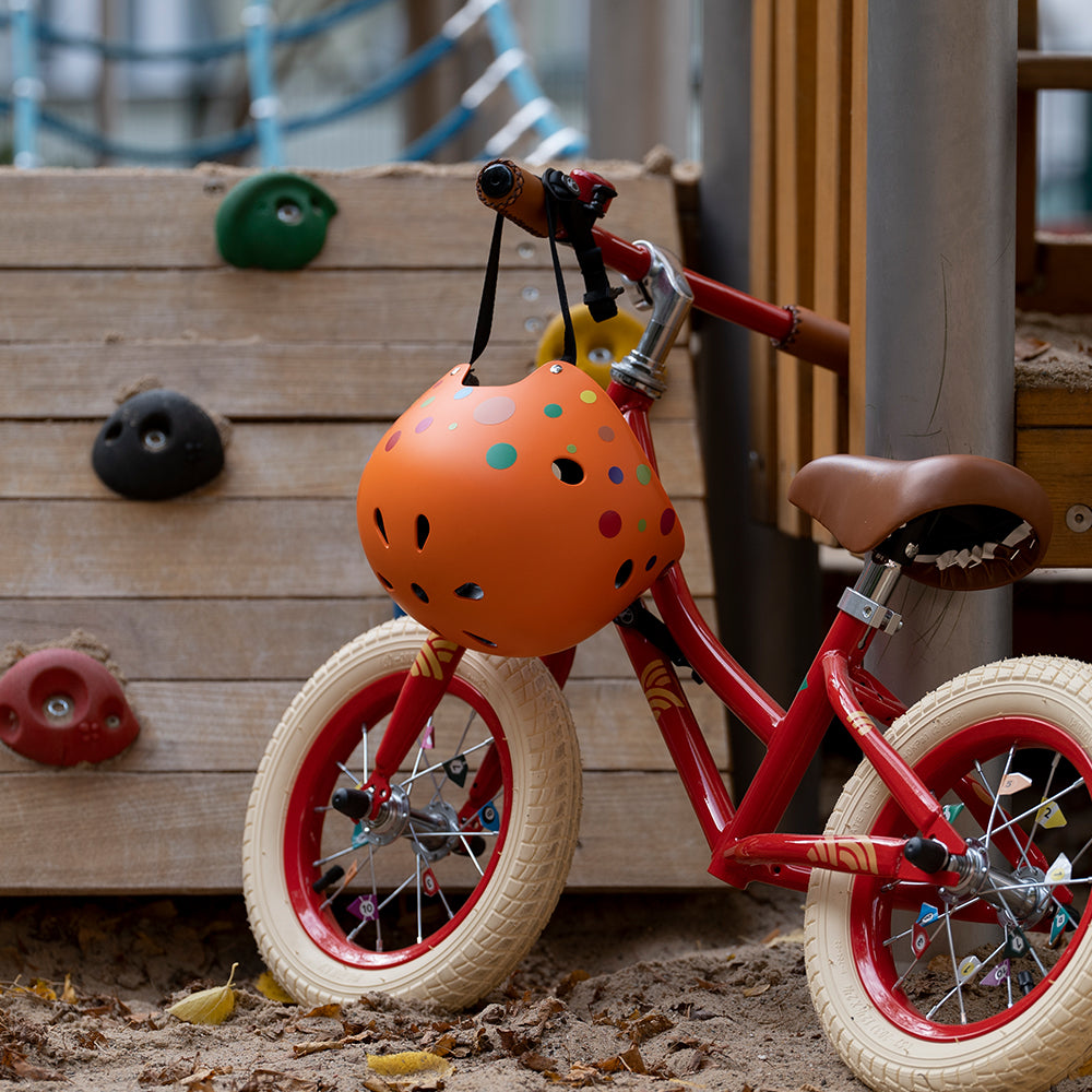 Kinderrad auf Spielplatz mit Helm und bunten Aufklebern