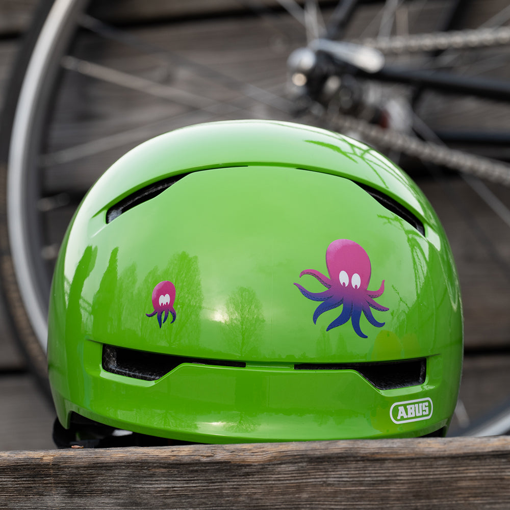 grüner Abus Fahrradhelm vor Fahrrad, mit lila Tintenfisch Aufklebern