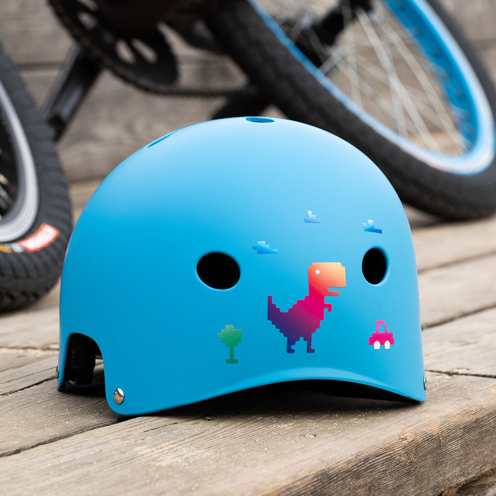 blauer Fahrradhelm für Kinder vor BMX, beklebt mit buntem Dinosaurier Aufkleber