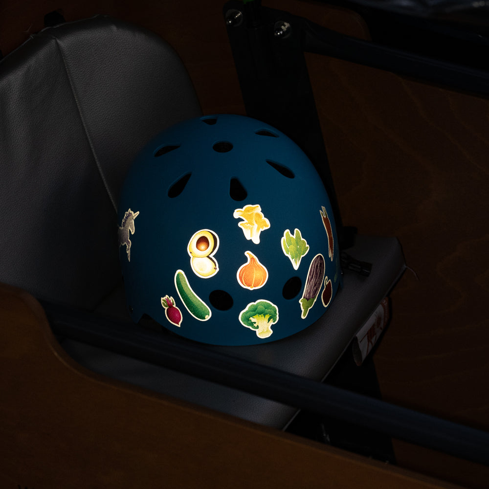 Blue helmet inside a cargo-bicycle box, with reflective veggies themed stickers