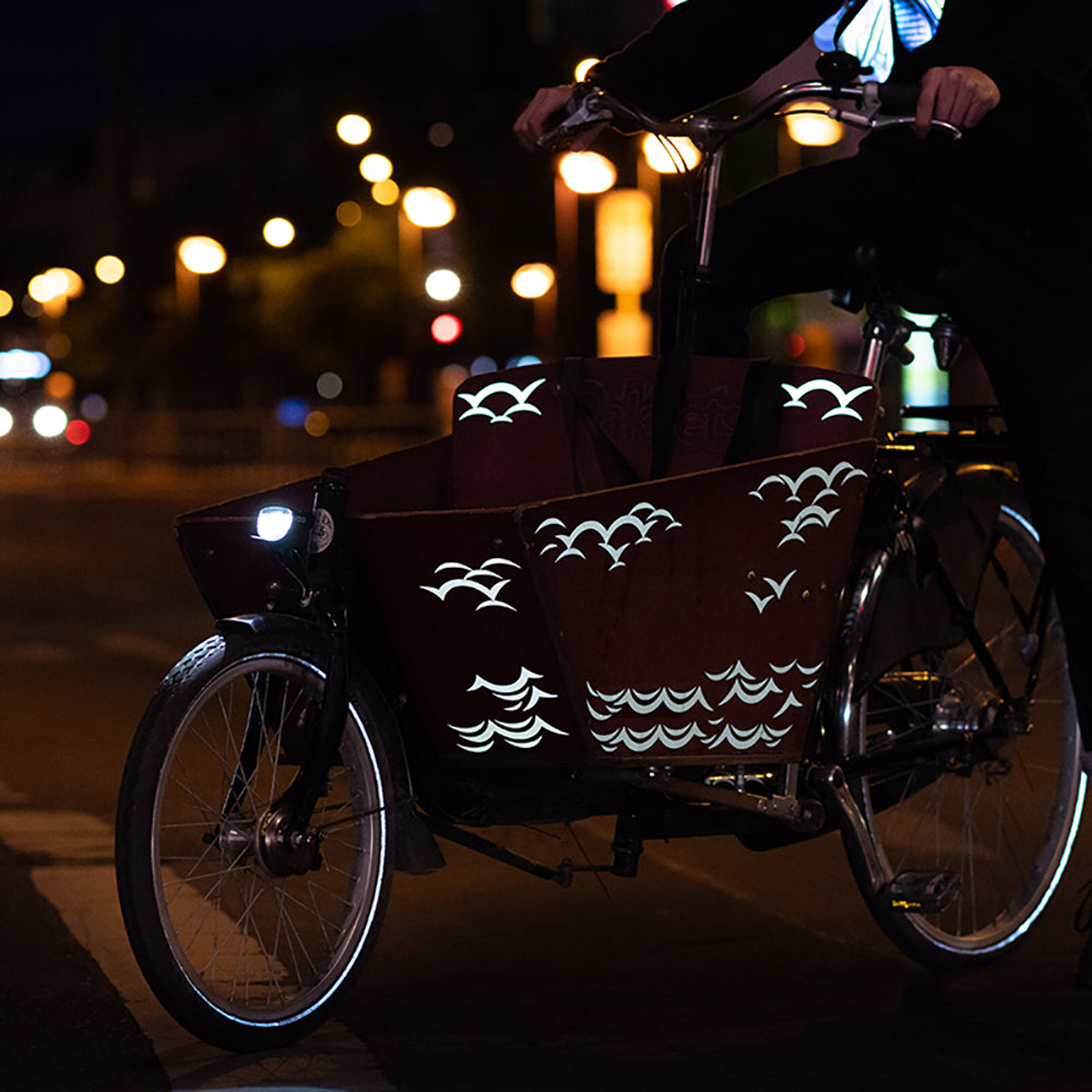 Bakfiets bei Nacht auf der Straße mit reflektierenden Aufklebern auf der Holzkiste